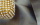 Detailaufnahme: Goldene Clutch mit Glitzersteinen auf grauem Glanzstoff